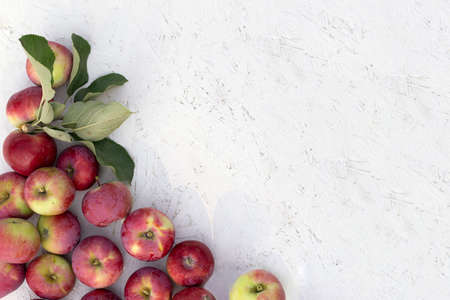 Fresh red apples with green leaves on white wooden surface wooden table. Top view with space for textの写真素材