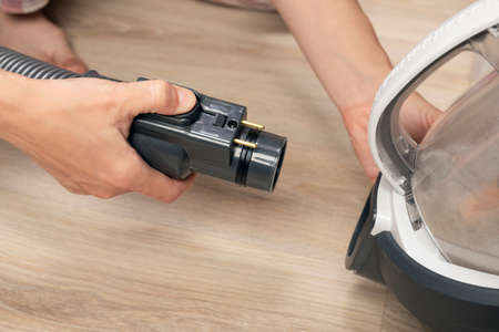 woman pulls out or inserts vacuum cleaner hose after or before use.の写真素材