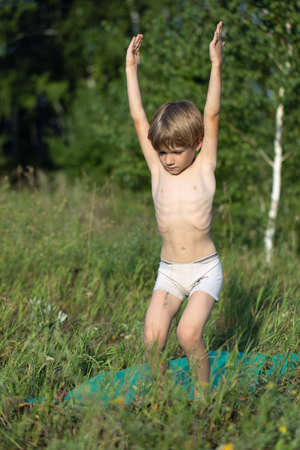 Boy in park is practicing yoga. Schoolboy doing yoga utkatasana position outside on open-air. Kids yogaの写真素材