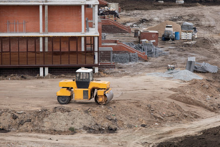 Buldozer making and constructing new asphalt road near civil building. Concepts of improvement of...