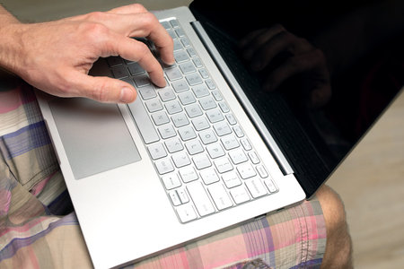 Adult man uses laptop while sitting at home. Online shopping concept, online games.