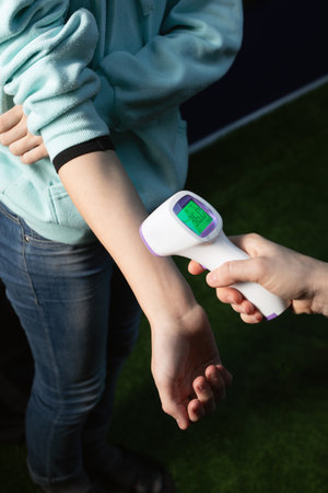 Digital thermometer gun for checking measurement shows 36degrees of body temperature in girl or...