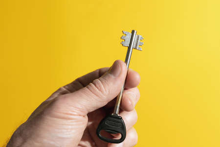 Male hand holding key on color background. concept of solution, success, opportunity.の写真素材