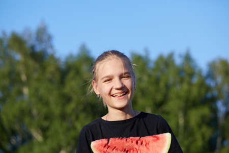 Happy young girl holding watermelon on nature background.の写真素材