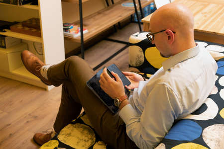 Handsome young man using phone while sitting on couch at home. free time activities.