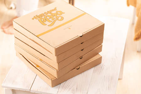 Pizza box, stack, brown, front view on dining table