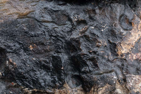 Relief area background with bumps and irregularities of black-brown color of burnt large stone...