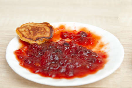 Breakfast. Fruit jam on a white plate with a pancake