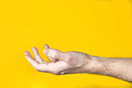 Man hand holding or taking something on yellow background.の写真素材