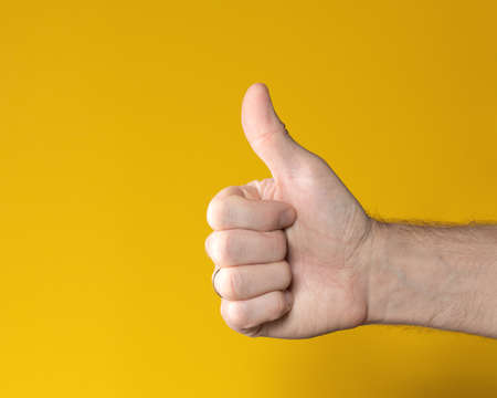 Man hand with thumb up isolated on yellow background. Showing like, positive sign. Symbol, icon of...