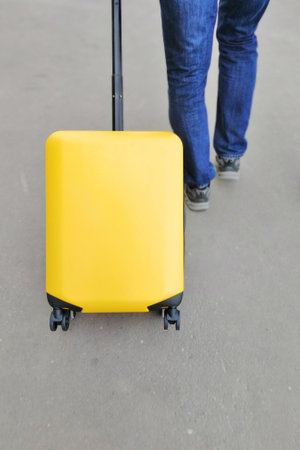 A man walks on an asphalt road and rolls a suitcaseの写真素材