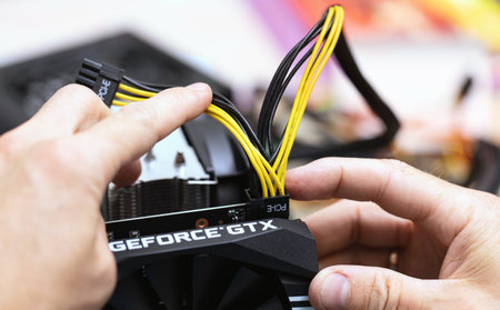 connecting power supply to video card by PCI-E 8 pin cable. Close up of person installing Computer...