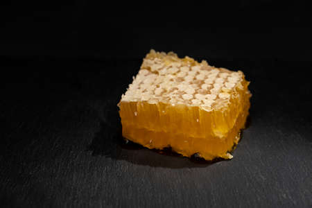 Sweet piece of honey in combs close-up on black background. Organic product theme