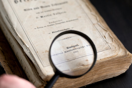 Magnifying glass over ancient german book of 1910 on dark background. Research of ancient literature. Russia, 27.12.2020のeditorial素材