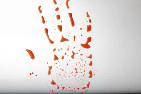 Red hand print a white dirty background. Concept of danger, the holiday of Halloween. Bloody red trail of a hand. red drops in the shape of a palmの写真素材