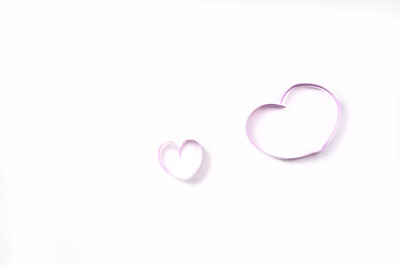 two hearts from a ribbon, a large and a small heart shape. Symbol of maternal love, pregnancy.の写真素材