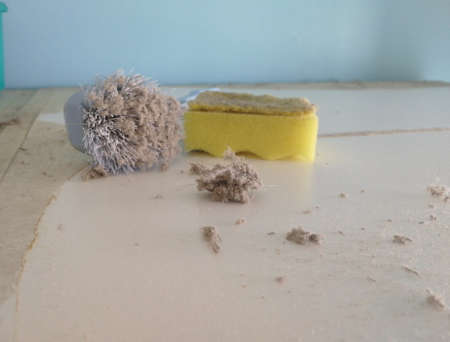 Cleaning dirty white surface with sponge and brush. Ball of common household dust. Shallow depth of...