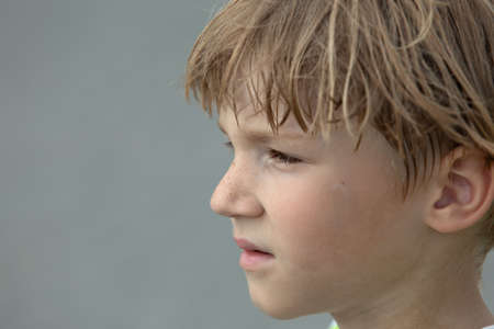 Close-up portrait of sad and thoughtful freckled teen boy looking away while contemplating