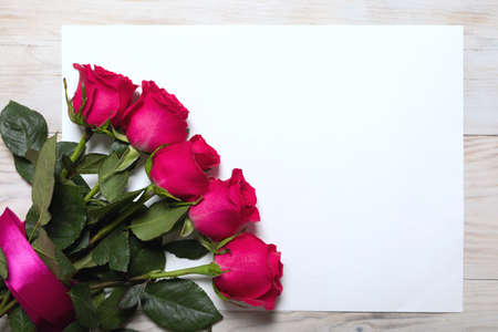 Elegant festive background with bouquet of pink roses tied with ribbon on white sheet of paper on...