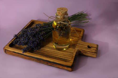 Lavender oil on a wooden tray on a pink background. Lavender oil and lavender bunchの写真素材