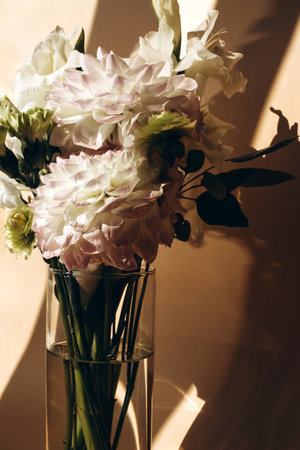 A bouquet of delicate light flowers in a glass vase with a shadow. Front viewの写真素材