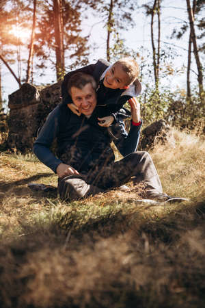 Boy and dad are having fun while walking in the forest on a sunny day. Father and son time togetherの写真素材