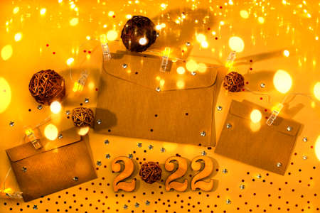 Craft envelopes on a yellow background with Christmas lights, red confetti and stars. Flat lay