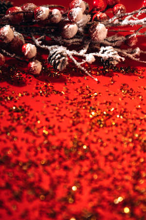 New Year, Xmas red background decorated with a decorative branch with red berries and golden confetti. Blurred backgroundの写真素材