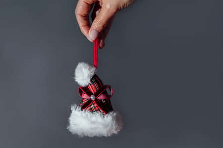 Christmas decorative toy in the form of a Santa hat in hand on a gray background. Preparing for Christmasの写真素材