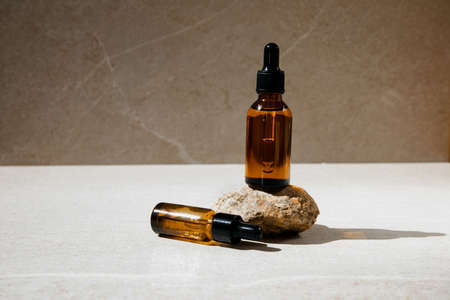 Clear bottles with natural SPA cosmetics on a beige stone background. Front view