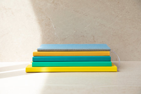 Multi-colored office notebooks on a light beige background, side view of the notebooks. Set of...