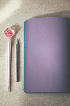 An open purple notebook and two pens for notes on a light table. Flat layの写真素材