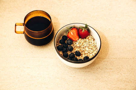 Healthy breakfast concept, oatmeal with fresh blueberries and strawberries with a cup of black coffee. Flat layの写真素材
