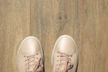 Light pink sneakers close-up on a wooden background. View from aboveの写真素材