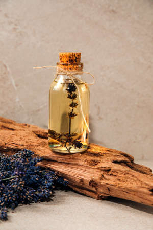 Lavender oil on a wooden stand on a light stone background with lavender flowers. Front viewの写真素材
