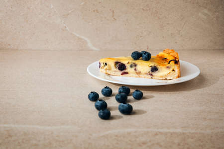 A piece of blueberry cheesecake on a white plate on a stone background. Front viewの写真素材
