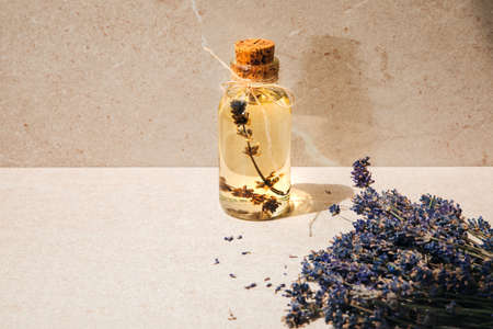 Lavender oil on light stone background with lavender flowers. Front viewの写真素材