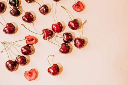 A large cherry with water drops close up on a light orange background in sunlight, selective focus. Top viewの写真素材