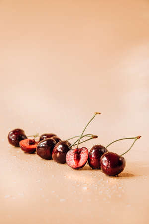 A large cherry with water drops close up on a light orange background in sunlight, selective focus....