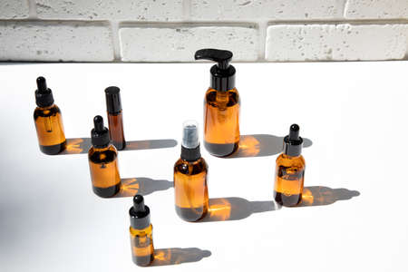 A group of amber bottles on a white table with face care products. A set of cosmetics in a glass package. Front viewの写真素材