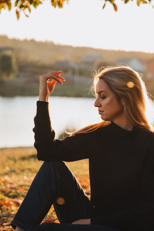 Beautiful girl with long blond hair in autumn landscape at sunset. Autumn portrait of a girl, front viewの写真素材