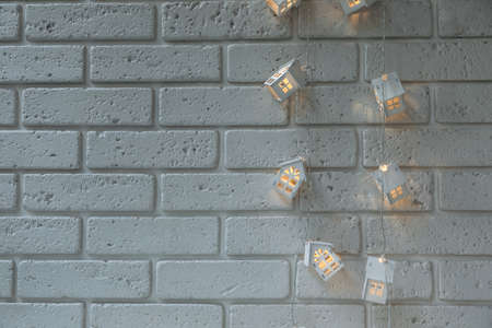Background of white brick wall with garland in the form of white wooden houses, structural...