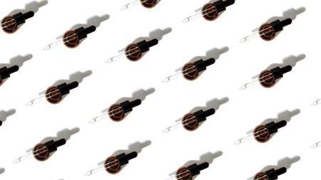 Pattern of open amber bottle with pipette on an white table with face care product. Top view, web bannerの写真素材