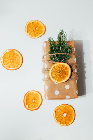 A gift in eco packaging, wrapped in brown paper with white circles and decorated with a dry orange...