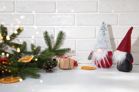 New Years, Christmas decor on a white table with branches of a green fir, pine cones, gnomes and orange. Front viewの写真素材