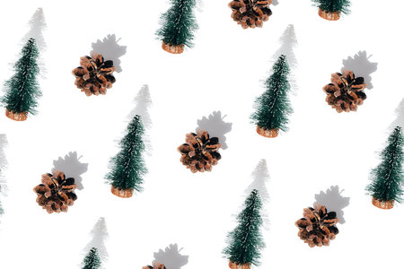 Background with small green decorative Christmas trees with shadows and pane cones on a white background. Flat lay Christmas patternの写真素材