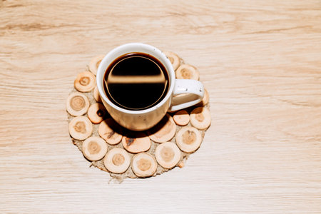 White large mug with black coffee on a wooden stand on the table. Top viewの写真素材