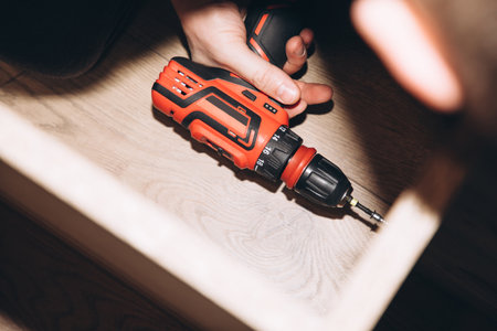 Close-up of male hands with a red screwdriver while assembling a cabinet. View from above, selective focusの写真素材