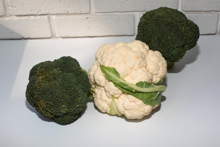 Broccoli, cauliflower on a white table with a white brick background. View from aboveの写真素材