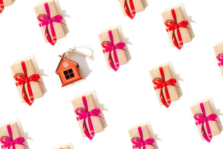 Background with gifts is tied with a red and pink ribbons with shadows and toy wooden house on a white background. Flat lay Christmas patternの写真素材